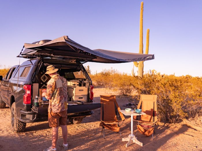 Outdoor camp kitchen setup with a comfortable chair and table, designed for vanlife adventures with the Roadloft camper kit.